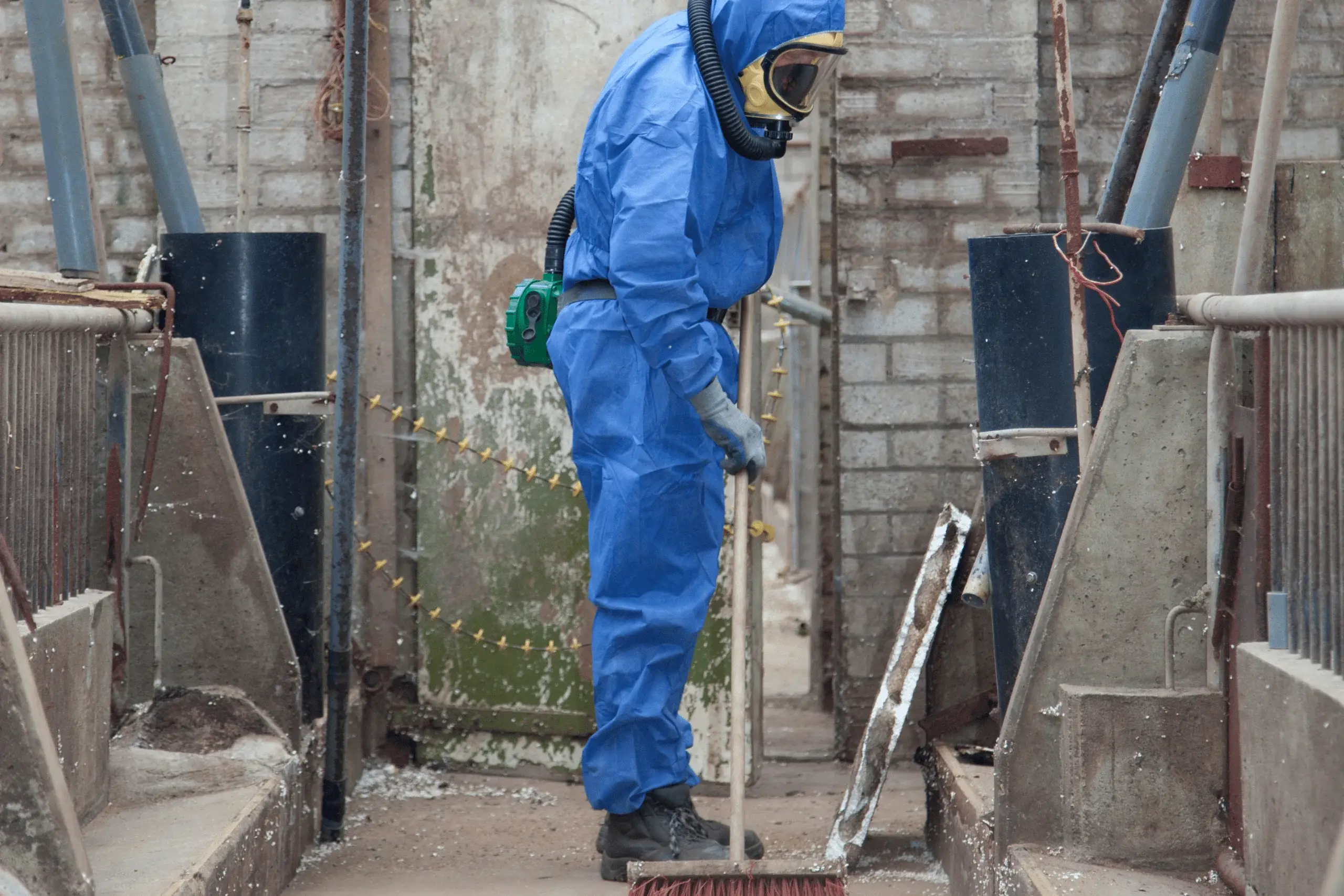 Hazardous material removal specialist cleaning up an industrial site with protective gear.