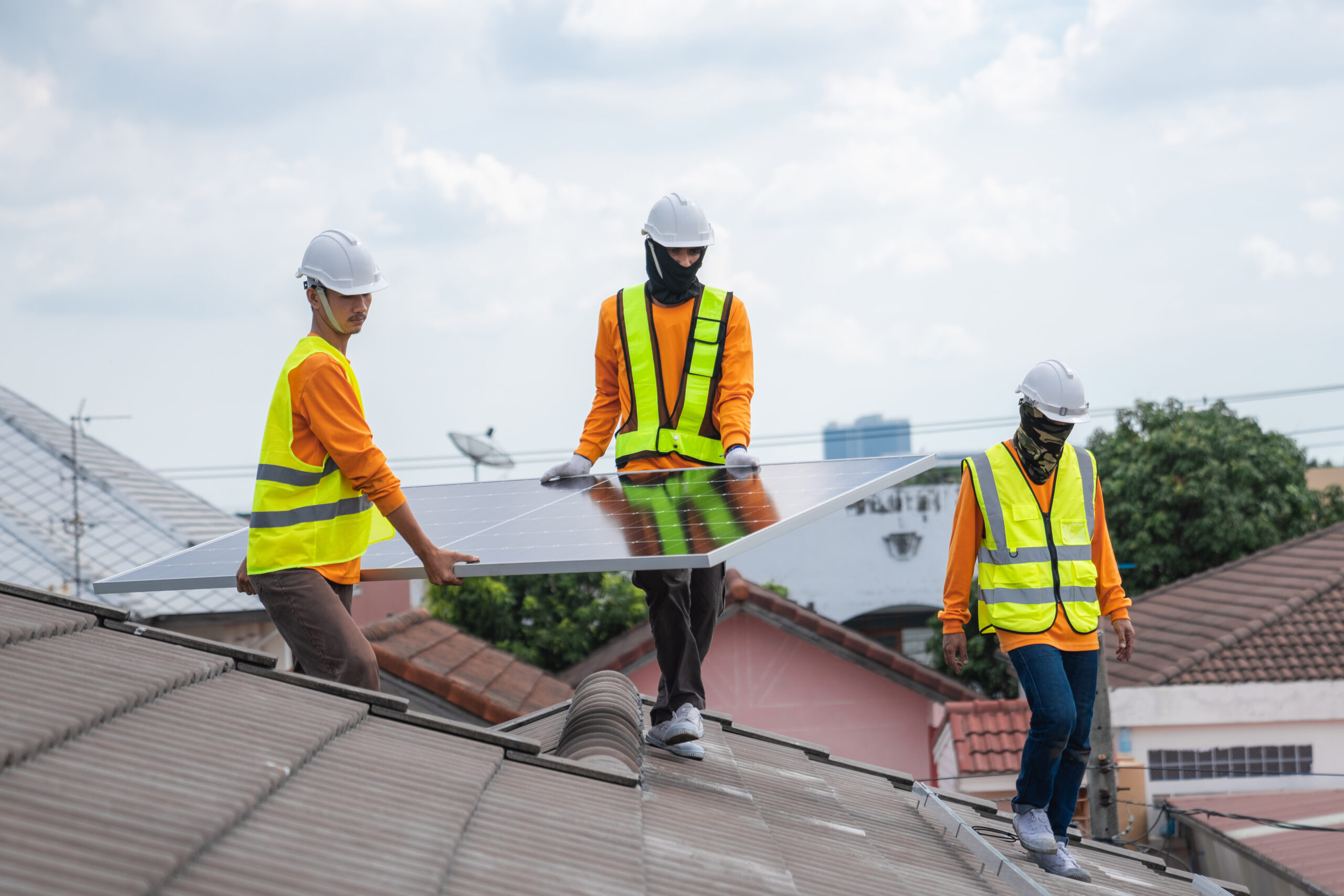 Roofing Services Lynn Heaven FL Service engineer installing solar cell on the roof of house. Technicians working about solar panel system outdoors. Clean and Renewable energy concept.