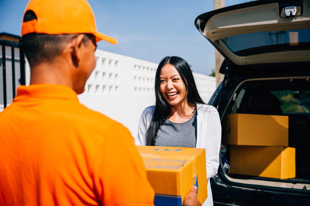 Transportation and Delivery in Rainey Way Efficient home delivery logistics depicted as a courier delivers a cardboard parcel to a smiling woman