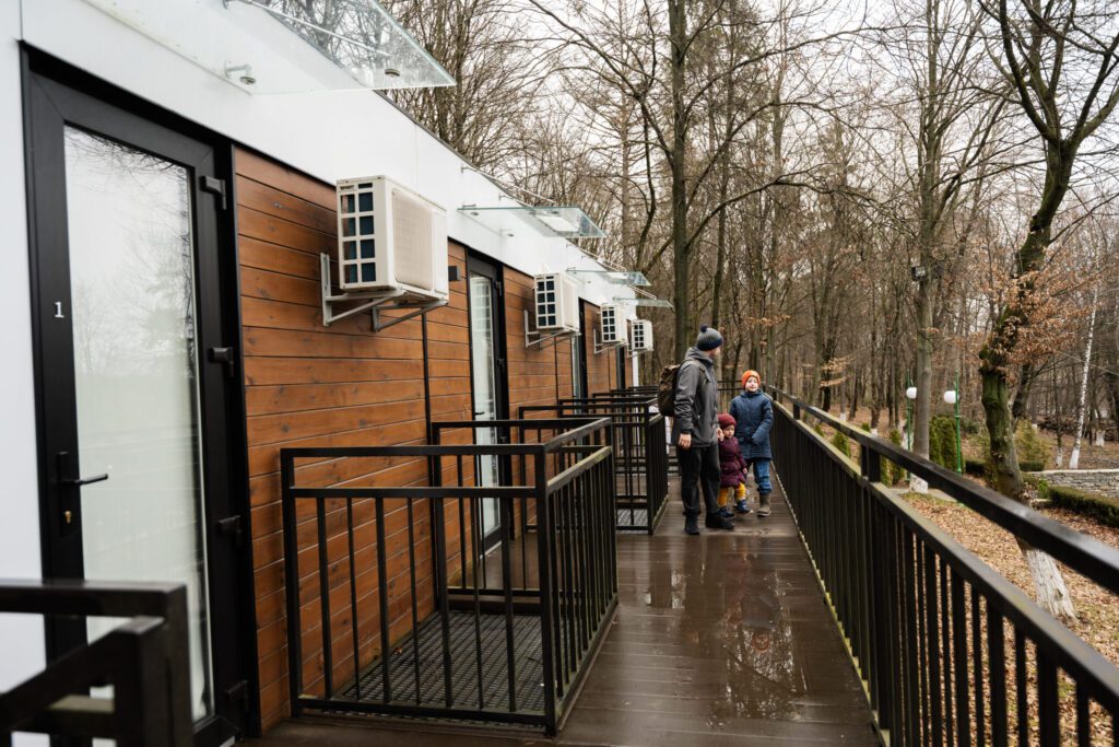 Tiny Buildings in Dartmouth, MA Father with three kids on terrace of one-storey modular houses i