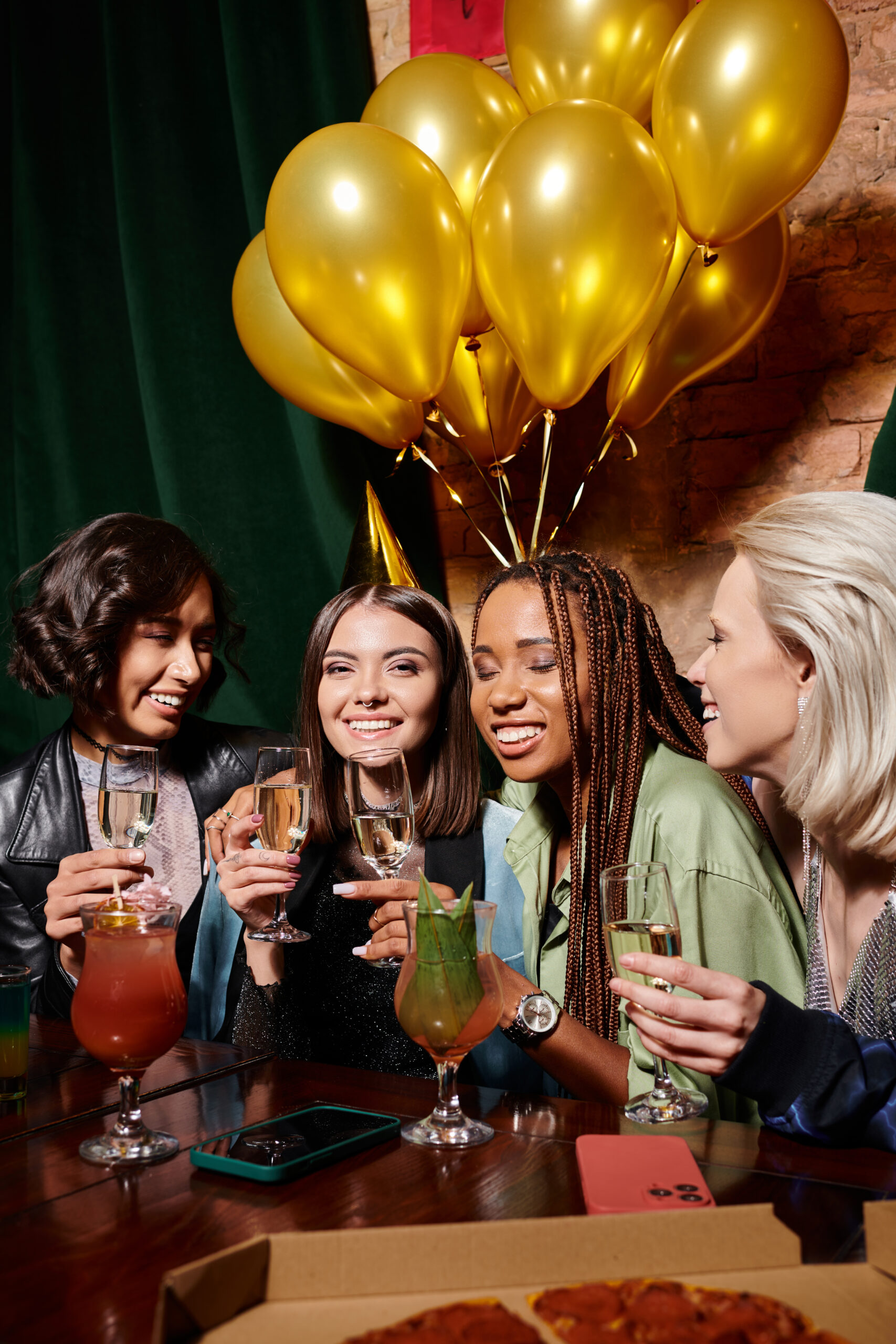 Birthday Party Bus Rentals West Chester OH happy woman in party hat with champagne near multiethnic girlfriends and birthday balloons in bar