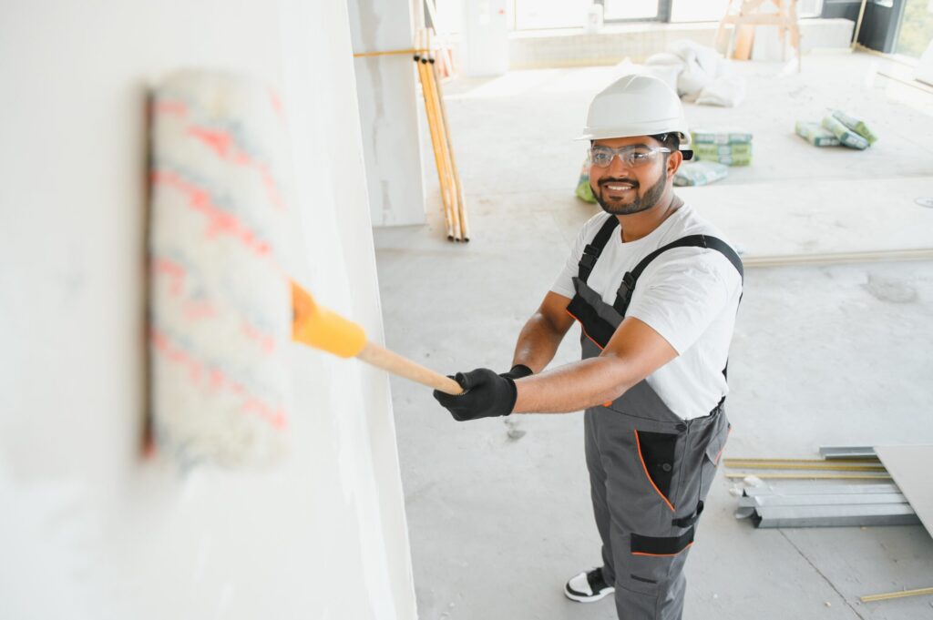 Drywall Installation Services in Panama City, FL An Indian apartment repair worker paints a white wall with a roller