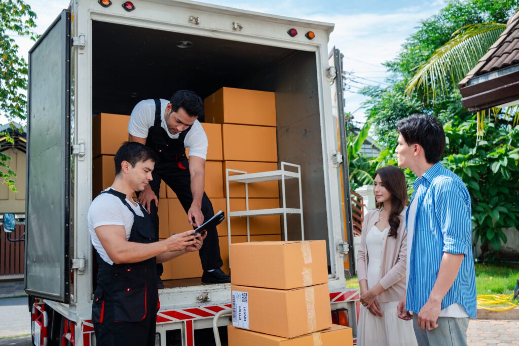 Home Relocation in Long Island, NY Asian Couple check while unloading boxes and furniture from a pickup truck to a new house with service cargo two men movers worker in uniform lifting boxes. concept of Home moving and delivery.