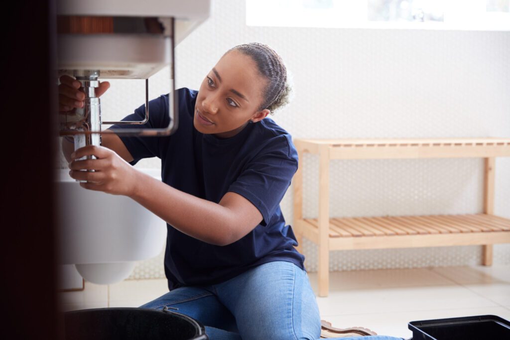 Licensed Plumbing Services Destin FL Female Plumber Working To Fix Leaking Sink In Home Bathroom